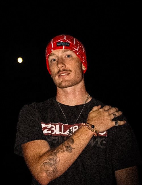Focused portrait of ProllyRed wearing a red beanie at night